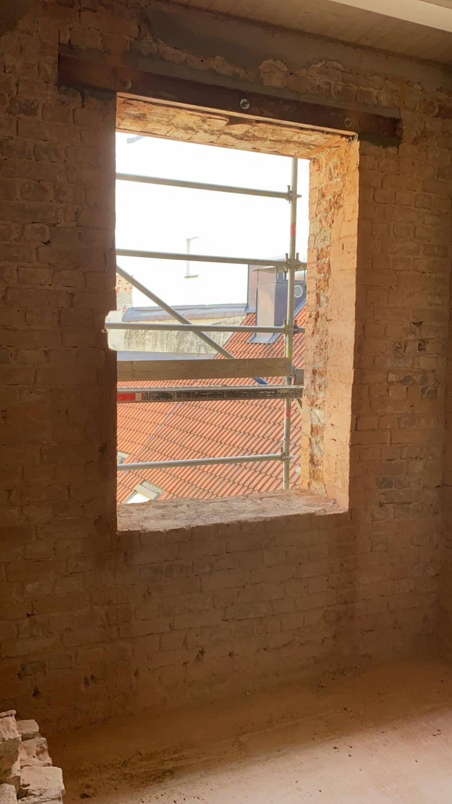 svaigi izzāģēta loga aila ēkas sienā ar dzelzs pārsedzi