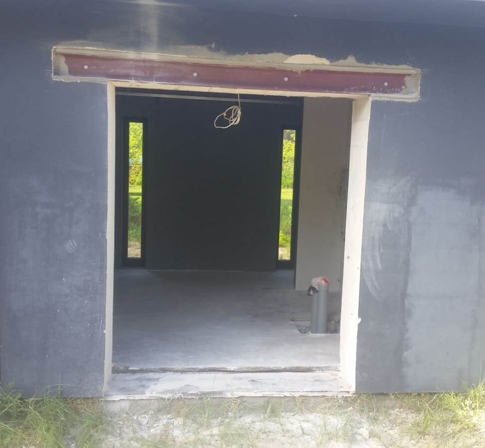 ēkas sienā izzāģēta durvju aila ar metāla pārsedzi
